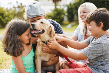 Young parents having fun with children and their pet outdoor at park in summer time - Focus on dog...