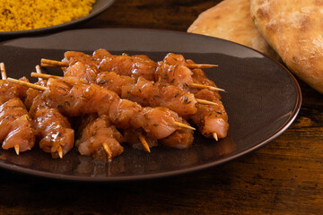 raw chicken skewer with tabbouleh in a dish on a table