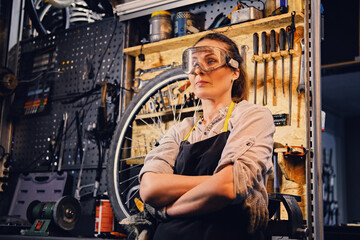 Fototapeta na wymiar Old woman with eyewear dressed in work wear in workshop