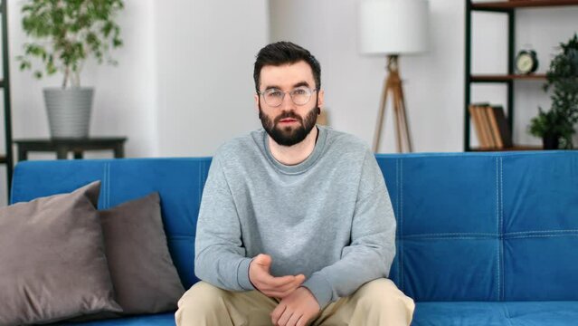 Trendy male blogger talking communication to auditorium spectators smiling sitting on couch
