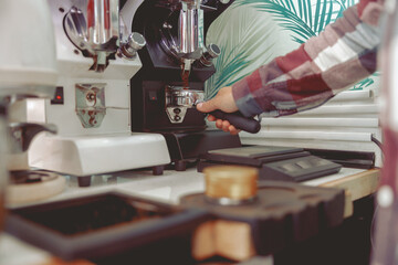Fototapeta na wymiar Close-up of male hand holding portfilter near coffee grinder