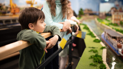 Portrait of little boy attentively watching displays in park of Wroclaw miniatures, Kolejkowo