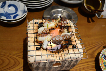 Selective focus of grilled octopus on charcoal stove. Food concept.