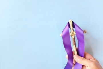 Top view of hand holding wooden cross crucifix with violet purple ribbon cloth with copy space. Holy week, lent season, Catholicism and Christianity concept.