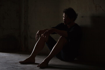 Fototapeta na wymiar Depressed and hopeless asian man sitting alone after using drugs sitting on the floor. Drugs addiction and withdrawal symptoms concept.