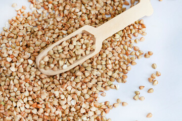 Buckwheat on light surface with wooden scoop and copy space
