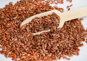 Linseed with wooden scoop on white background