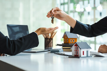 Estate agent giving house keys to customer after contract signature.