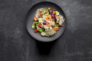Caesar salad with shrimps on a black background