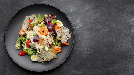 Caesar salad with shrimps on a black background