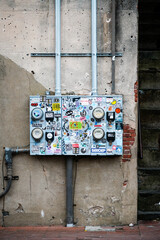 Electric power meters in urband environment with colorful stickers on vintage stucco wall