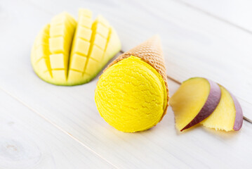 Ice cream with mango in a waffle cone on a wooden table.