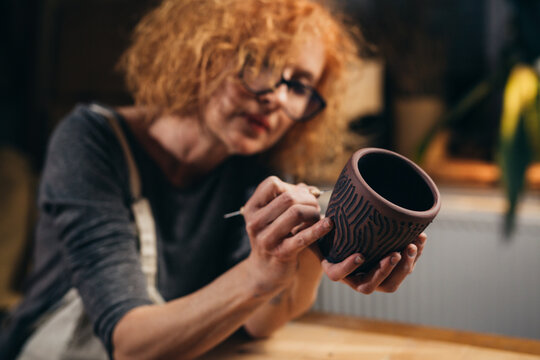 woman is carving pottery in her workshop