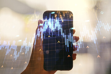 Double exposure of abstract creative financial chart with world map and hand with cell phone on background, research and strategy concept