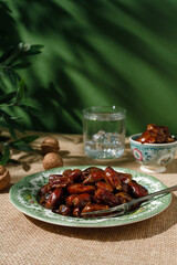 Dried dates in a green vintage plate on a brown textile background. Rustic style