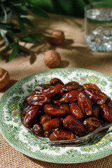 Dried dates in a green vintage plate on a brown textile background. Rustic style