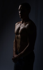 Fototapeta premium muscular silhouette black background. athletic young man. Black and white dark contrast photo of fitness muscular arms and chest. strong athletic man.