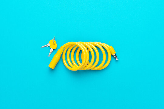 Yellow bike lock with keys over turquoise blue background. Top down flat lay photo of bicycle lock with central composition.