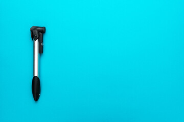 Bicycle pump over turquoise blue background with copy space. Top down flat lay photo of compact bike pump.