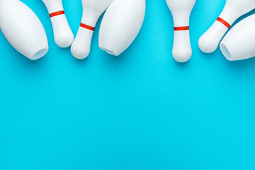 Minimalist photo of bowling pins over turquoise blue background. Flat lay top down image of white bowling pins with copy space. - obrazy, fototapety, plakaty