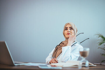 Front view of a beautiful doctor, a beautiful Muslim woman in uniform with a stethoscope, who is meditating in a hospital clinic. One person who has expertise in professional treatment.