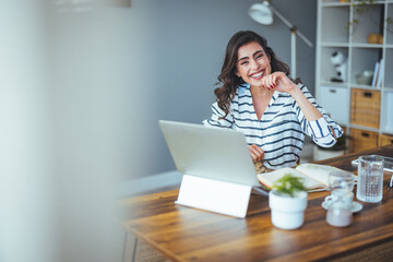 A portrait of a happy successful Caucasian businesswoman in casual clothes looking and smiling at the camera. An attractive manager is sitting at a table after a hard day's work