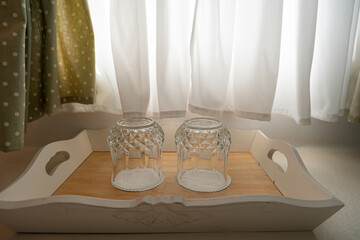Water glass on wood tray for customer near window with curtains in vintage style in luxury hotel...