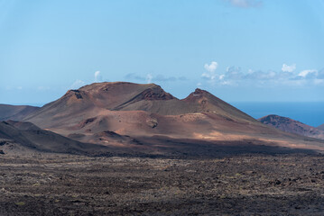 Fototapeta na wymiar Impresionante paisaje volcánico con un gran volcán inactivo en el Parque Nacional de Timanfaya en Lanzarote, Islas Canarias, durante un día soleado con el cielo azul despejado. Recursos naturales 