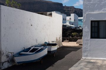Calle del pueblo Orzola en Lanzarote, Islas Canarias, con dos pequeños barcos pesqueros apoyados...