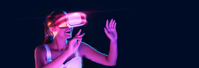 Excited young lady using VR glasses, neon studio