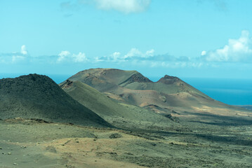 Imagen panor&aacute;mica de un paisaje des&eacute;rtico con dos grandes volcanes y el mar de fondo en el parque nacional de Timanfaya. Recursos tur&iacute;sticos de naturaleza de Lanzarote en las Islas Canarias.