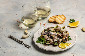 Escargots de Bourgogne or Snails with herbs, butter, garlic on metal plate with forks. wine glass. gourmet food. Restaurant menu, dieting, cookbook recipe