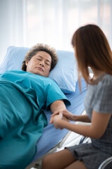 health insurance concept, young Asian woman are visit her senior family patient at hospital room, grandmother sitting on wheelchair are sick and having health care support by doctor and nurse