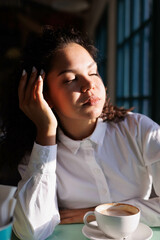 Serious curly girl in cafe, thoughful. Woman drinking coffee cappucino in restaurant.
Young girl thoughtful with some problem