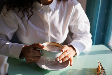 Serious curly girl in cafe, thoughful. Woman drinking coffee cappucino in restaurant.
Young girl thoughtful with some problem