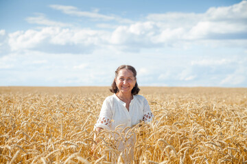 Naklejka na ściany i meble Portrait of happy smiling senior woman in wheat field