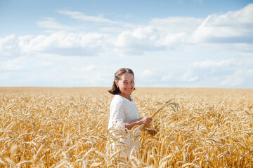 Naklejka na ściany i meble Portrait of happy smiling senior woman in wheat field