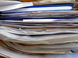 Big pile of news papers, documents, magazines on a shelf in the office.