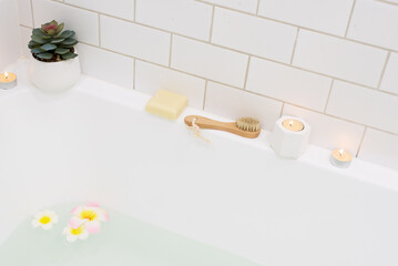 Bathtub with Plumerria Flowers and Inflatable Flamingo Toy Ring with Drink Bamboo Face Brush Home SPA Concept Relax