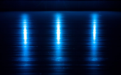 Smooth, shiny surface of an ice rink with reflected by spotlights. Dark empty ice arena with soft blue light. Concept of winter sports games, hockey, figure skating. Close up.