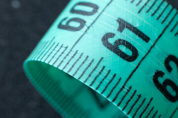 Close-up of rolled up tape measure on number 61. Slim waist and healthy weight concept