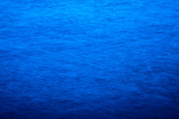 Background and texture of the surface of an ice rink in blue light, sports stadium for hockey or figure skating. Surface of the stadium fret with scratches, streaks and skate marks. Close up.