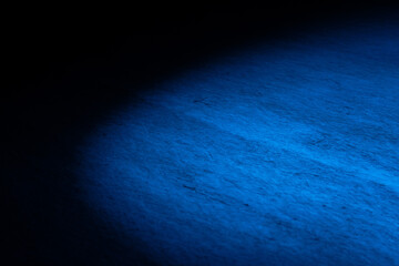 Dark empty ice arena illuminated by blue spotlights. Beam of light is reflected from ice surface....
