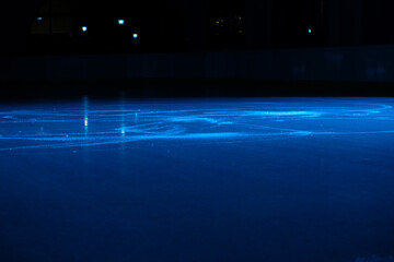 Smooth, shiny surface of an ice rink with reflected by spotlights. Dark empty ice arena with soft...