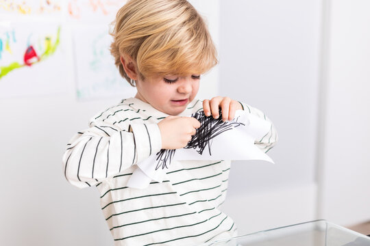 Upset boy tearing paper with strokes
