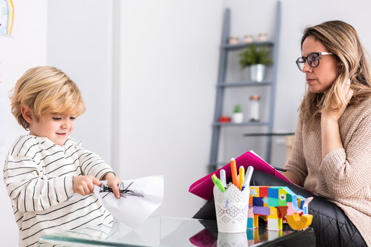 Boy tearing paper near psychologist