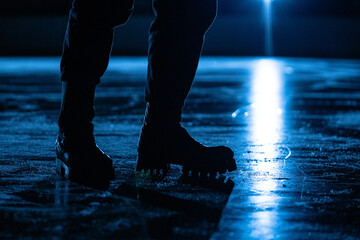 Men's legs in rough boots on the ice of a sports arena. A male coach stands on surface of an ice...