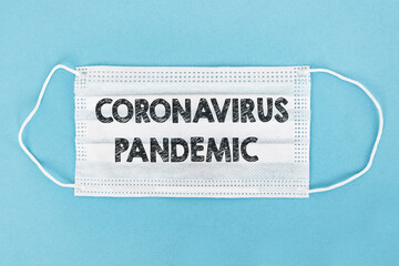 Coronavirus Pandemic text written on white surgical mask on blue background. Virus Pandemic Protection Concept
