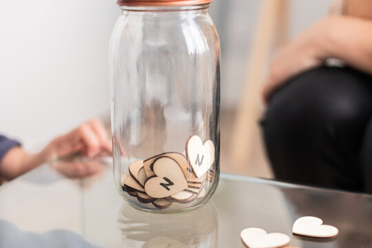 Glass jar with letters on wooden hearts