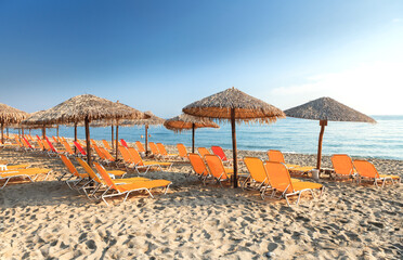 Sonnenschirme am Meer. Sonnenschirme und Sonnenliegen am Strand.  
Leerer Morgenstrand. Sommerferien-Banner.